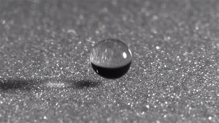 Wassertropfen auf Sand in Zeitlupe